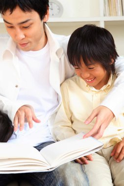 Asyalı baba ve oğul evde kitap okuyorlar. 