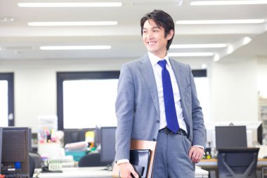 Ofiste klasörleri tutan takım elbiseli ve kravatlı bir adam. 