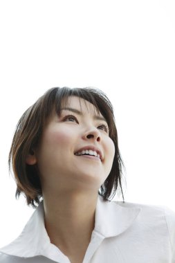 Asyalı bir kadının gülümseyip yukarı baktığı 