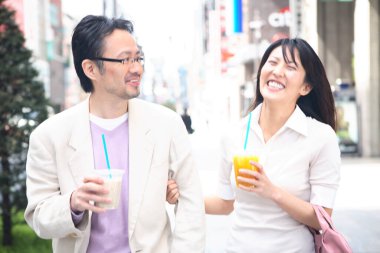 Bir adam ve bir kadın ellerinde içkilerle sokakta yürüyorlar.