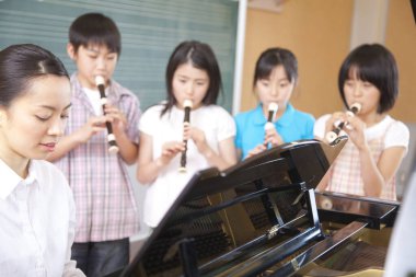 Müzik sınıfındaki bir grup çocuk enstrümanlarla oynuyor.