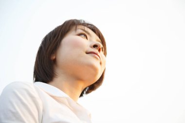 Genç Asyalı kadın gülümsüyor, dışarı bakıyor.