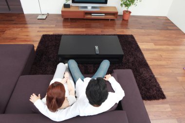 Kanepede oturup televizyon izleyen bir çift.