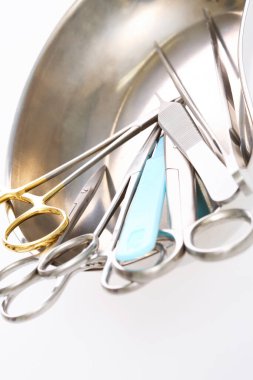 Metal kasede beyaz arka planda ameliyat için farklı tıbbi gereçler.