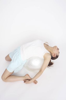 Beyaz arka planda izole edilmiş top ile spor yapan Asyalı genç kız. 