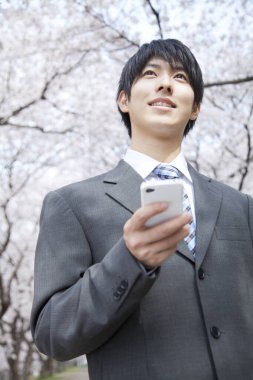 Parkta cep telefonu kullanan Asyalı bir adam.