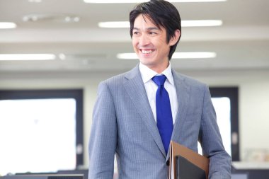 Ofiste klasörleri tutan takım elbiseli ve kravatlı bir adam. 