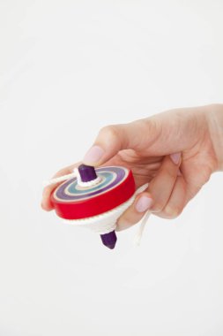 Kadın eli ahşap dönen klasik oyuncağı tutuyor. Beyaz arkaplanda girdap oyuncağı