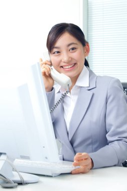 Genç Asyalı iş kadını telefonda konuşuyor. 