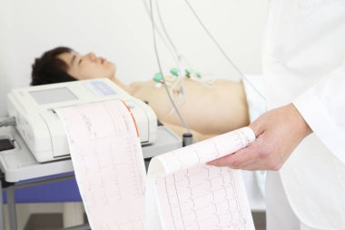 Doktor hastanın kalbine elektrokardiyogram (EKG) uyguluyor.