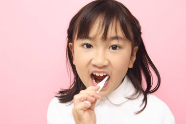Diş fırçasıyla dişlerini fırçalayan Asyalı küçük kız.