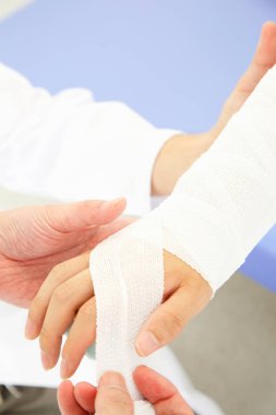 Doktor hastanın koluna bandaj koydu, kesilmiş bir fotoğraf. 