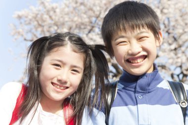 Sırt çantalı gülümseyen Japon çocuklar bahar parkında