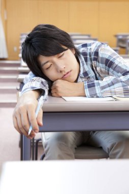 Genç Asyalı öğrenci üniversitede uyuyor.
