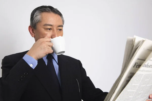 asian man drinking coffe and reading  newspaper