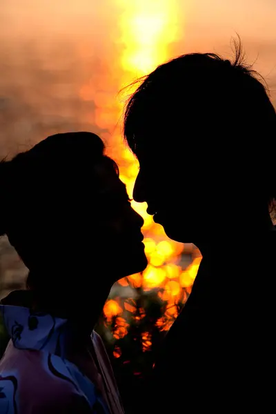 close up asian couple in love posing against sunset, moon light reflection on water