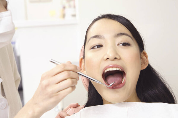 young asian  woman getting her teeth treatment at dentist office 