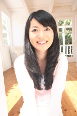 Asyalı kadın evde oturuyor.