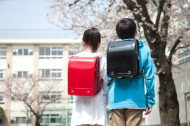 Okul bahçesinde kiraz çiçeği arayan genç Japon ilkokul öğrencilerinin geçmişe bakış.