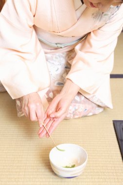 Kapalı kadın geleneksel Japon çayı hazırlıyor. 
