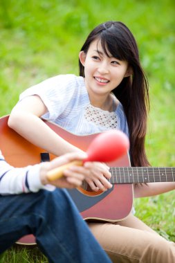 Doğada Guiter çalan Asyalı kadın 