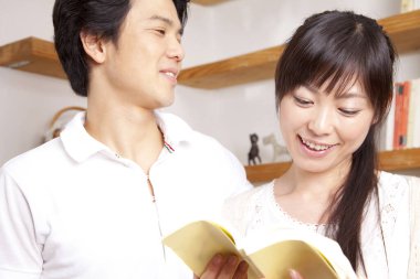 Genç çift evde kitap okuyor. 