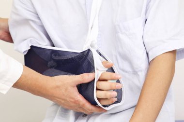 Tedavi ve iyileşme sürecinde hastaya kol askısında yardım eden doktor..