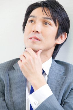 asian man in a suit and tie looking up in office 