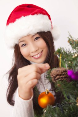 Ağacın yanında Noel süslemesi olan Asyalı kadın.