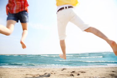 Kumsalda havaya atlayan iki insan.