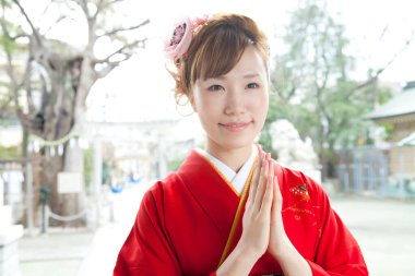 Geleneksel kırmızı kimonolu güzel Asyalı kadın tapınakta dua ediyor.