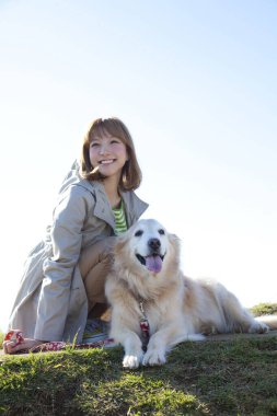 Çimlerin üzerinde köpeği olan genç Asyalı kadın.