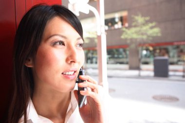 Bir kadın dışarıda dururken cep telefonuyla konuşuyor.