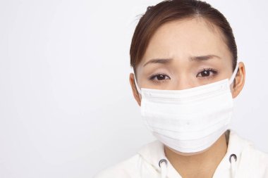 Yüz maskesi takan Asyalı kadın beyaz arka planda izole edilmiş.  