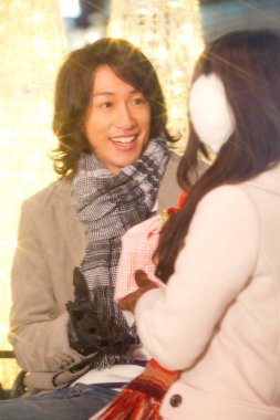 Aşık mutlu Asyalı çift, erkek kız arkadaşına hediye sunar. 