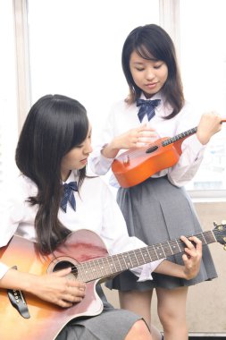 Gitar ve gitar çalan Asyalı liseli kızlar 