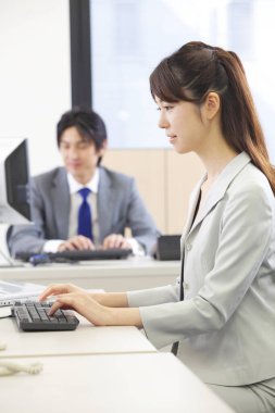 Masada oturan bir kadın bilgisayar kullanıyor.