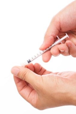 Adamın elleri beyaz arka planda bir şırınga tutuyor. 