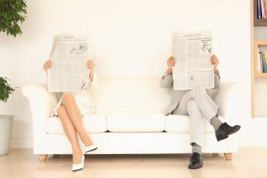 Sandalyelerde oturan ve içeride gazete okuyan genç işadamları.