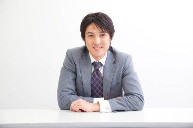 Takım elbiseli Japon işadamı masada oturuyor.