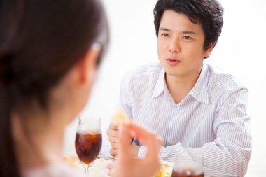 Erkek, bir kadınla yemek yerken konuşuyor.