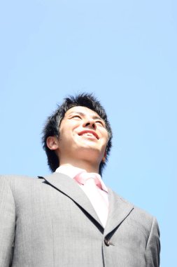 portrait of a  young asian businessman on sky background 