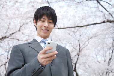 Park 'ta cep telefonu kullanan Asyalı adam. 