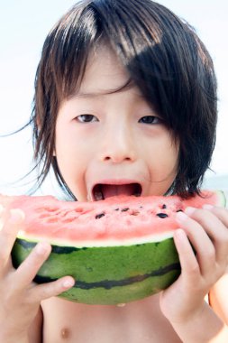 portrait of a cute boy eating  a watermelon
