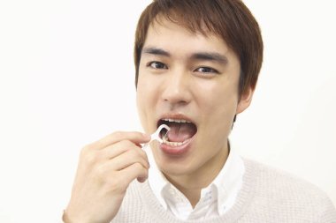 Dişleri temizlemek için diş ipi kullanan Japon 'un stüdyo portresi.