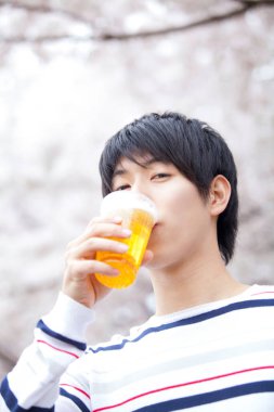 Asyalı adam bahçede bira içiyor.