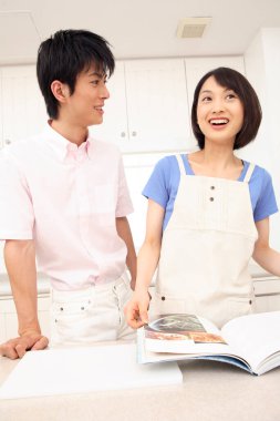 Asyalı çift birlikte yemek tarifi okuyor.