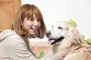 Golden retriever köpeği olan güzel Asyalı bir kadın.