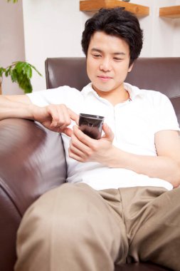 Genç bir adamın portresi akıllı telefonuyla evde dinleniyor. 