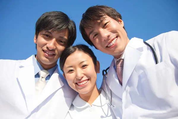 三位年轻的亚洲医生站在我们的门口 — 图库照片